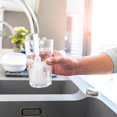 person filling glass of water from sink